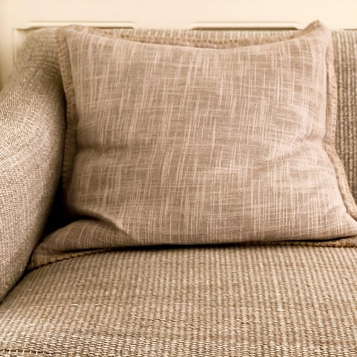 front corner view of textured gray sofa with decorative throw pillow