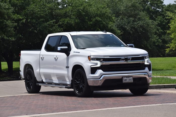A new white 2024 Chevy Silverado pick-up truck cruising near a park