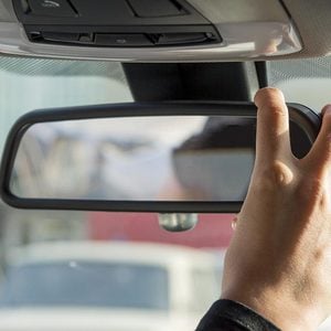 girl adjusts the rearview mirror in a car