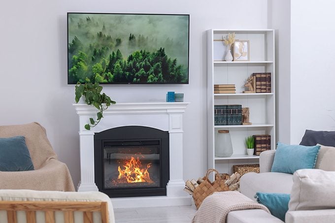 Stylish living room interior with cozy sofa, TV set and fireplace