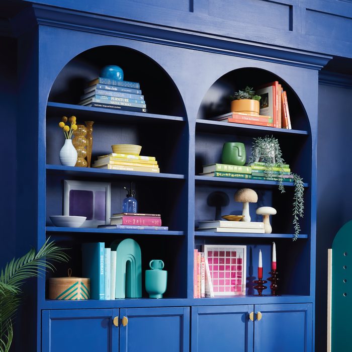A blue bookshelf displays colorful books and decorative items, including vases, plants, and sculptures, creating an artistic and vibrant interior space.