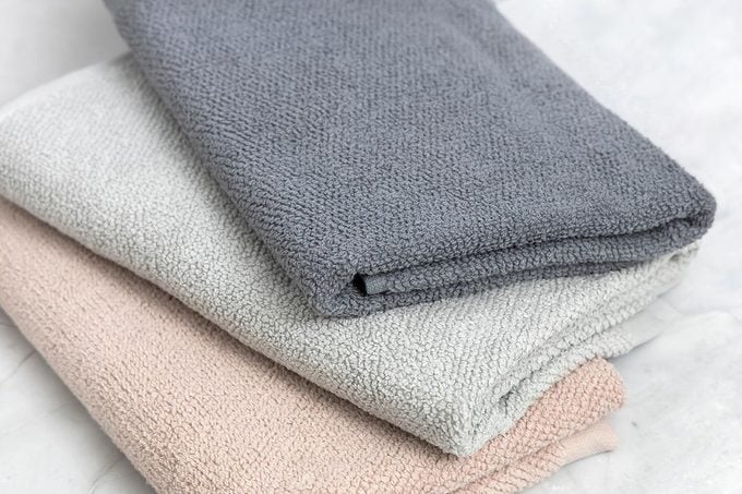 Folded clean towels on white marble background.